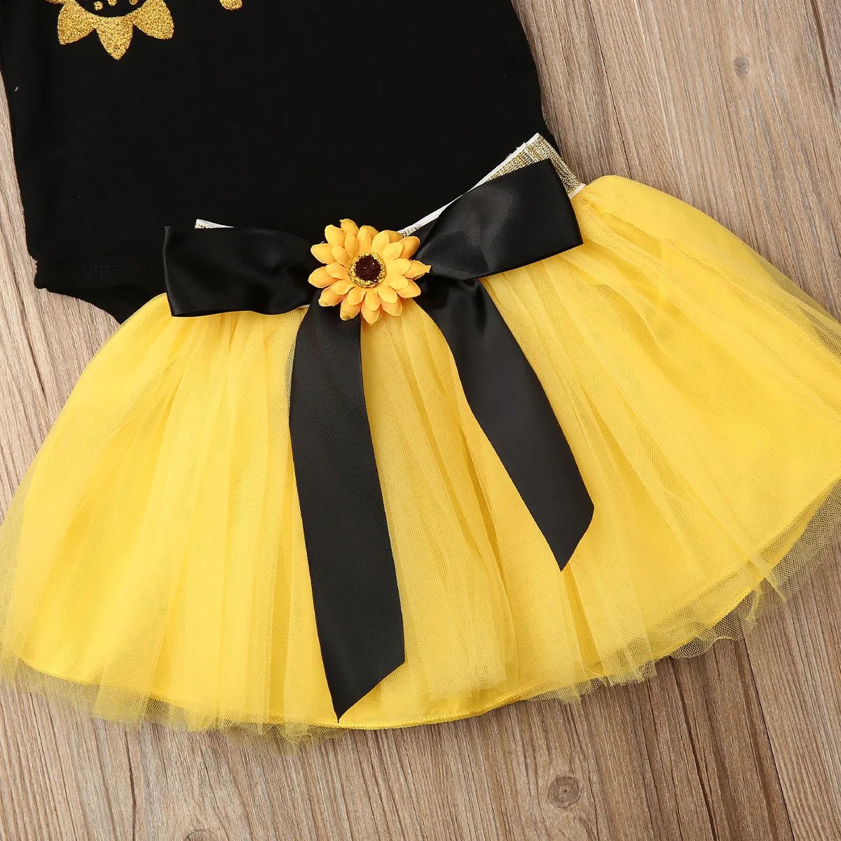 Yellow tutu skirt with black ribbon and sunflower trim for baby girl birthday outfits and photo styling.